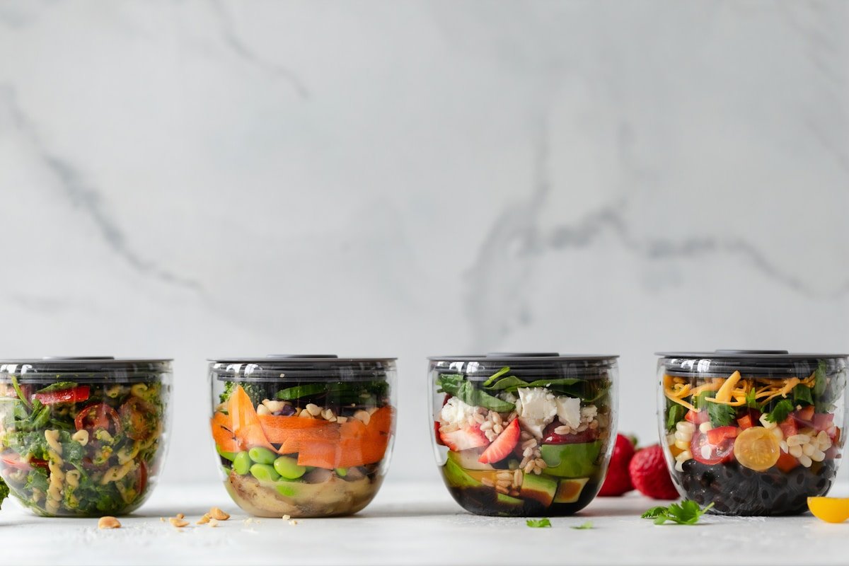 Clear plastic meal prep containers with vegetables and protein portions ready for the week