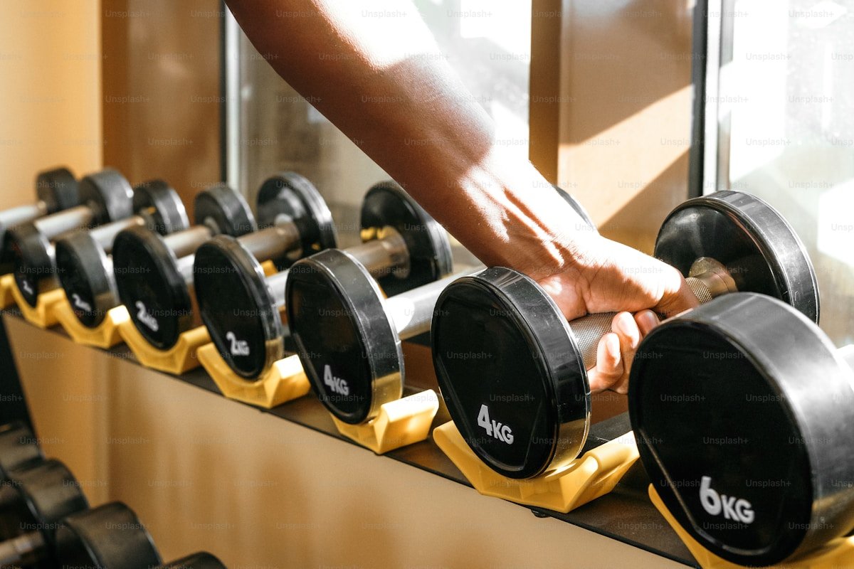 Person at gym holding water bottle during strength training session for fat loss