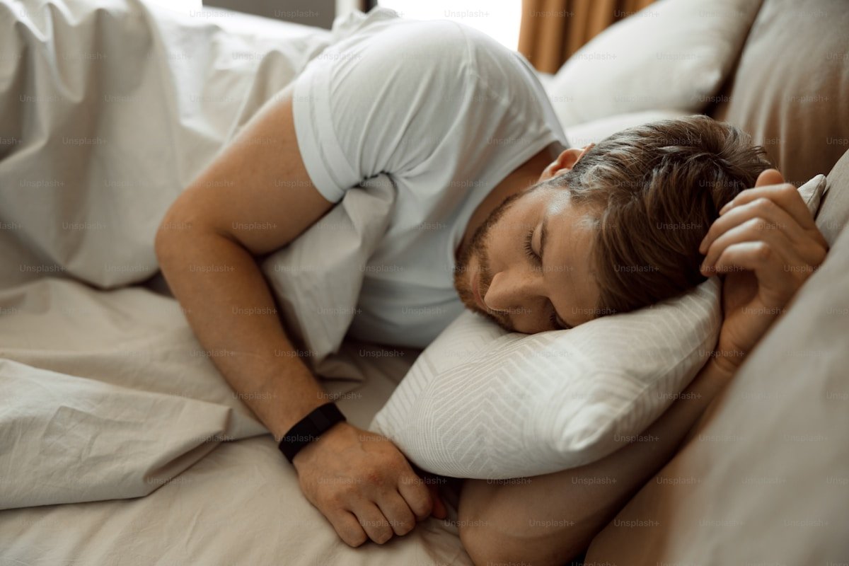 Young man sleeping in bed demonstrating rest and recovery for weight management