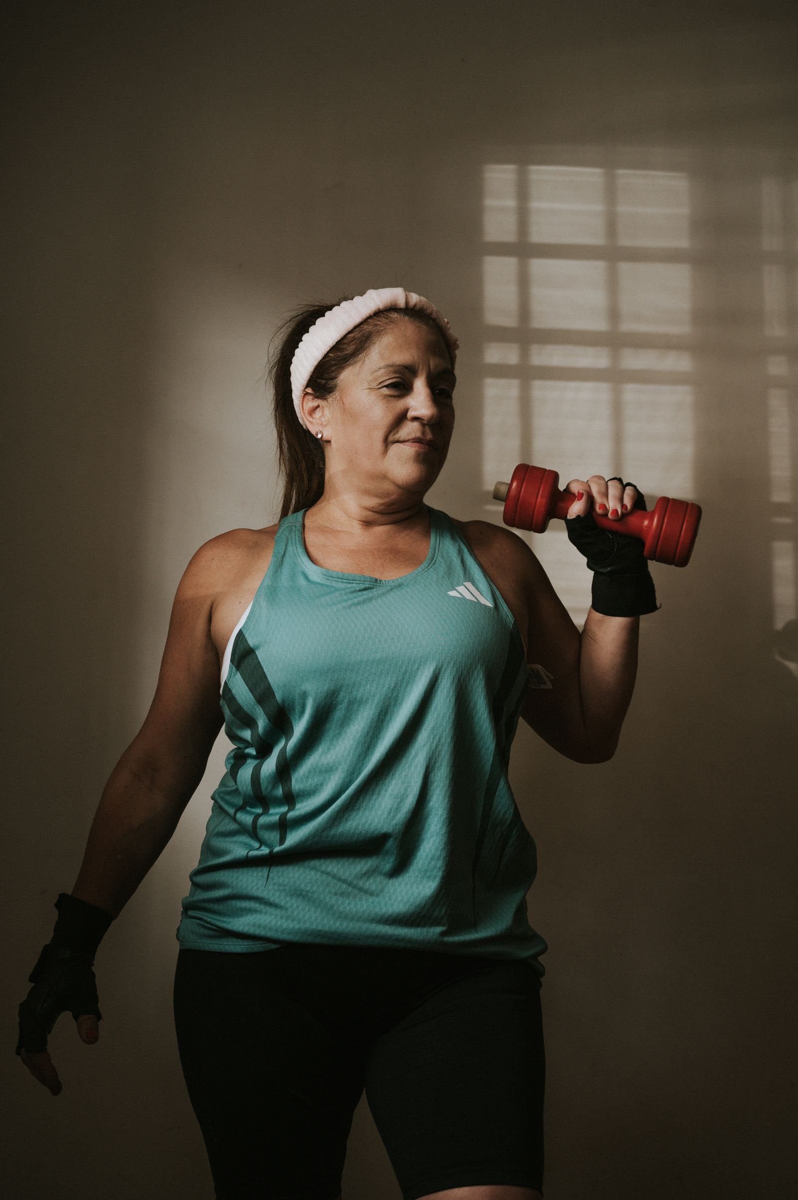 Woman in midlife performing a dumbbell strength exercise as part of menopause-friendly fat-loss training