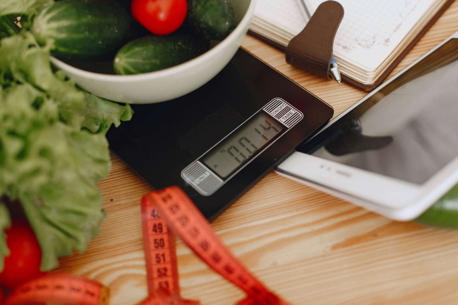 Kitchen scale and notebook used to audit portions and oils during a weight loss plateau tracking check