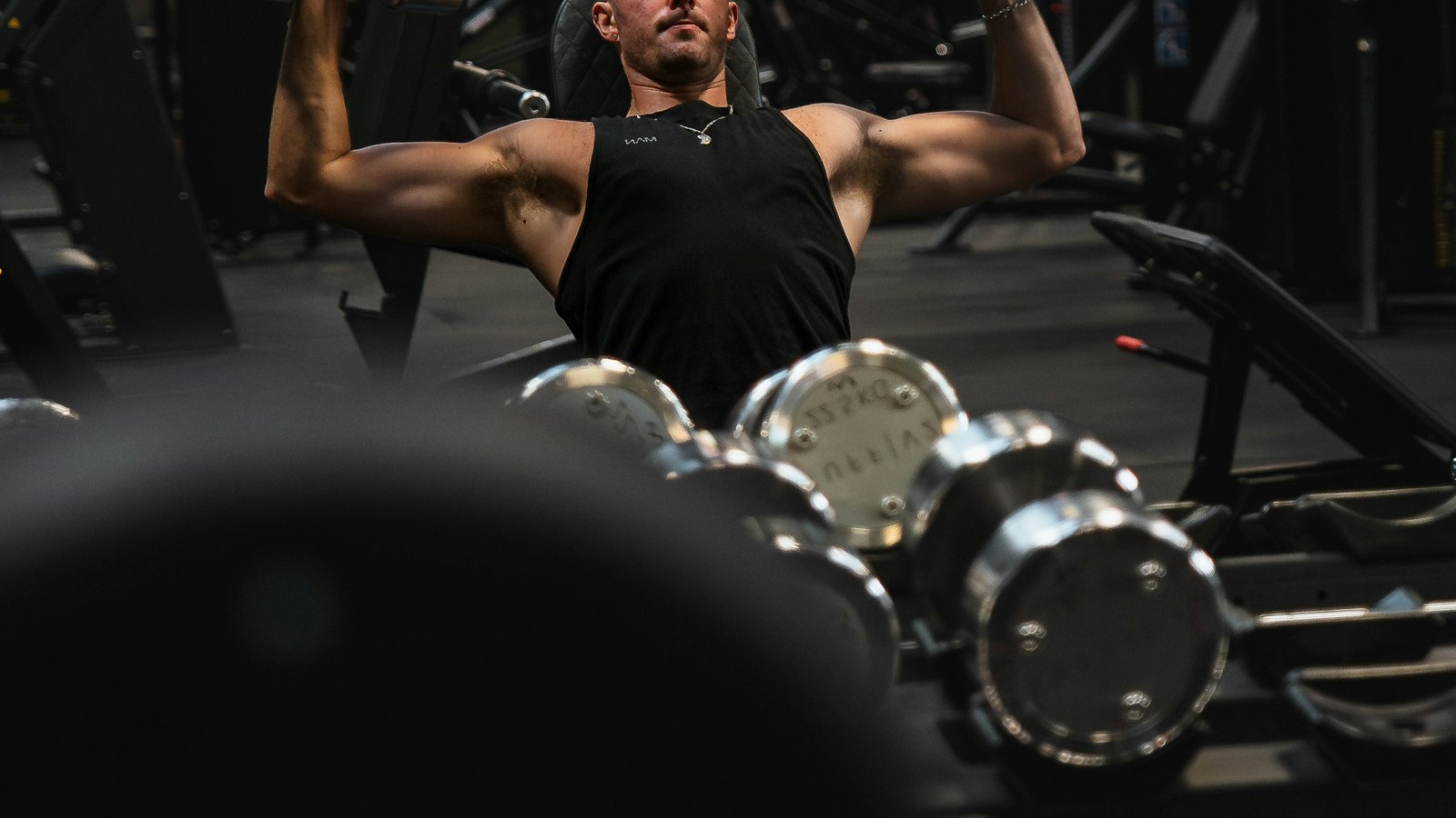 Man lifting dumbbells on a gym bench during a resistance-training workout