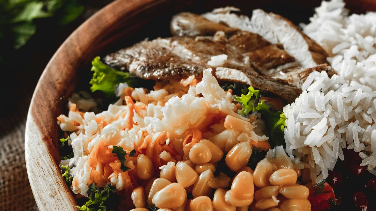 Balanced protein meal with grilled chicken, beans, rice, and leafy greens in a bowl